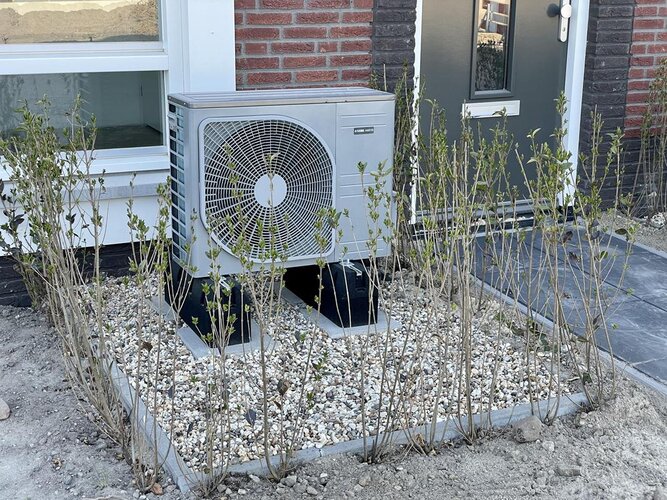 Techniker inspiziert eine Außen-Wärmepumpe an einem Einfamilienhaus